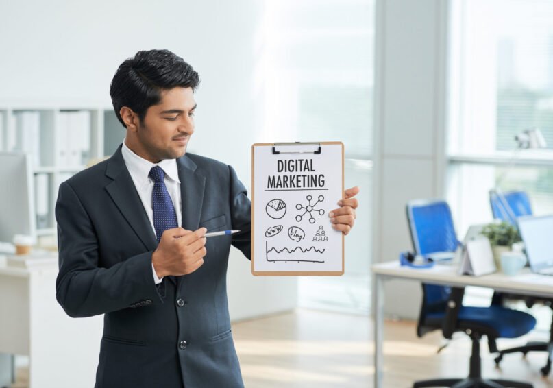 man-suit-standing-office-with-clipboard-pointing-poster-with-words (1)